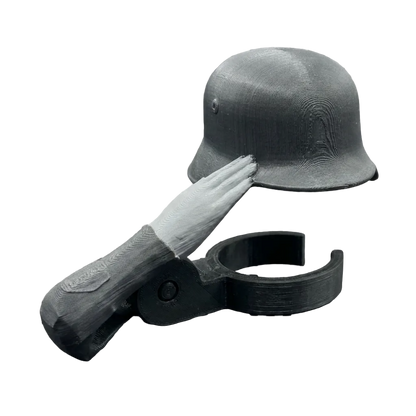 A miniature black helmet with a white hand saluting, mounted on a black plastic clip, shown against a black-and-white checkered transparency background.
